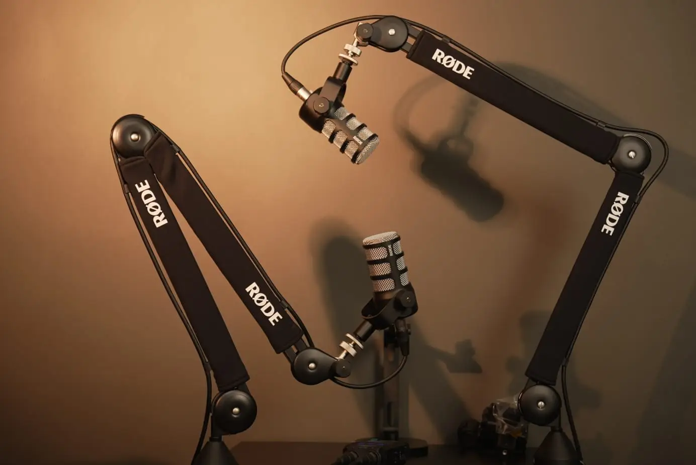 Two RØDE broadcast microphones on boom arms set up for podcast recording at Onqol studio